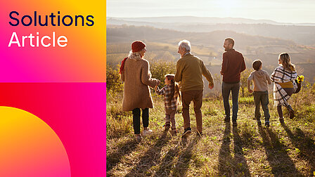 Mehrgenerationenfamilie spaziert durch eine Landschaft bei tiefstehender Sonne.