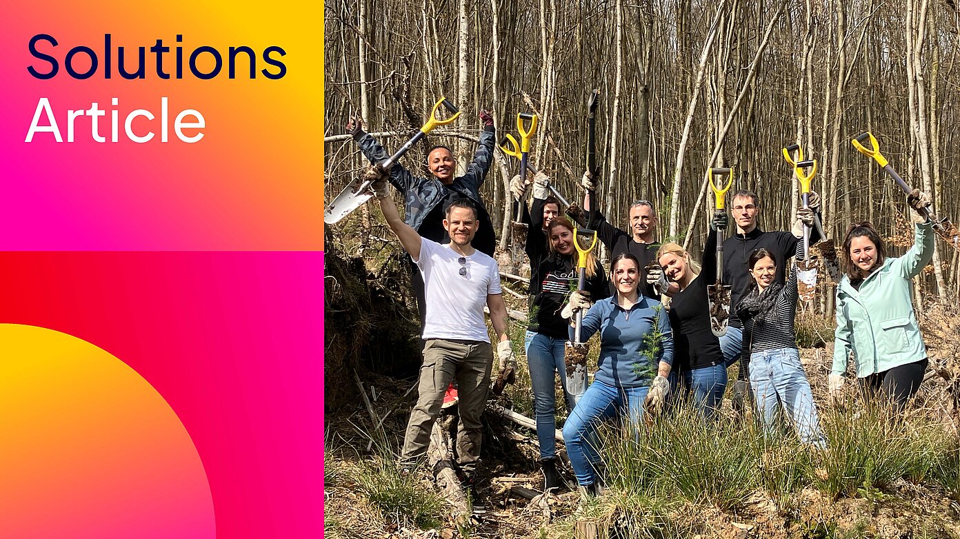 Team der FI-SP pflanzt im Wald Setzlinge, hält Spaten hoch – Baumpflanzaktion.